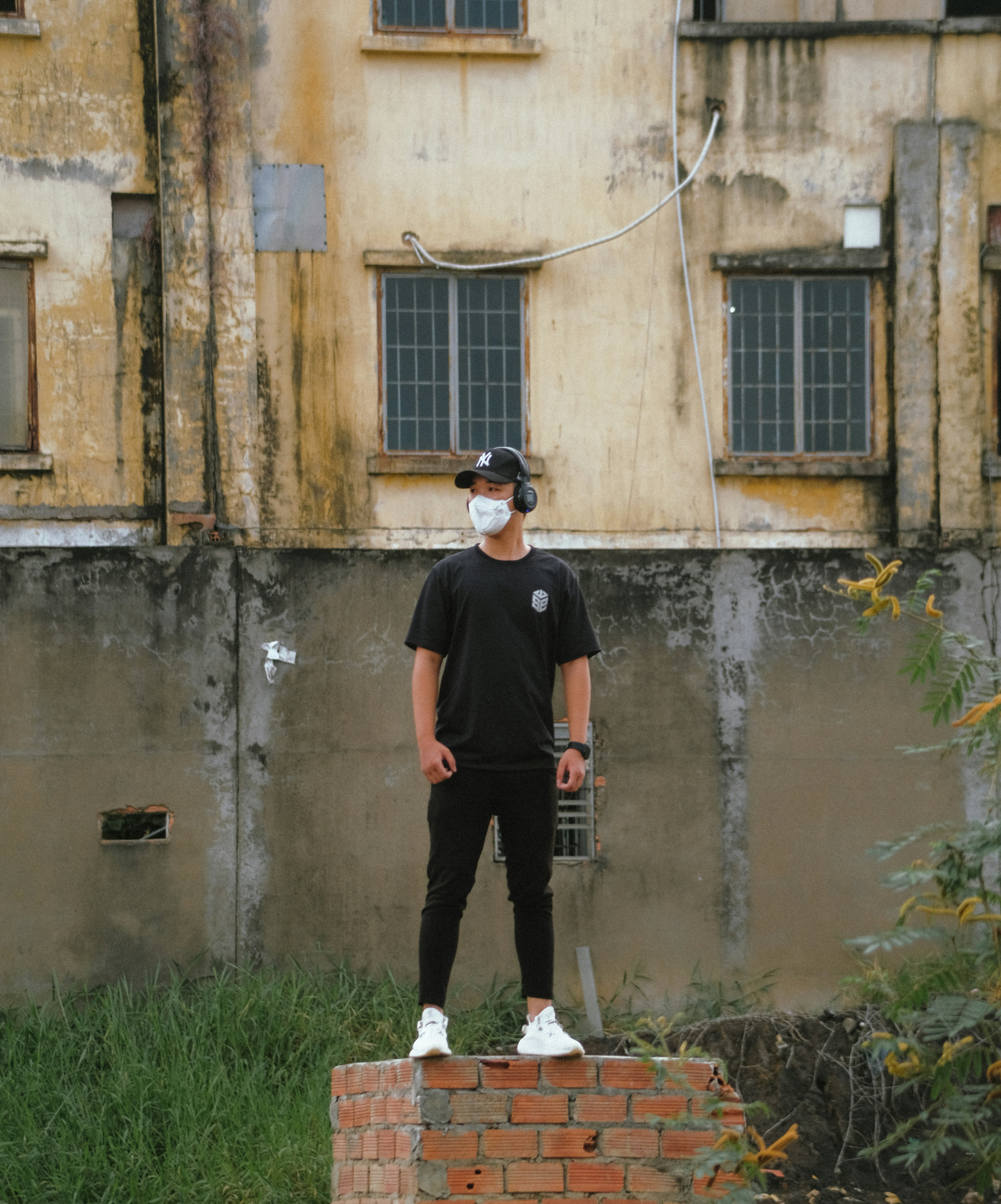 man in black crew neck t-shirt and black pants standing beside brown concrete building during